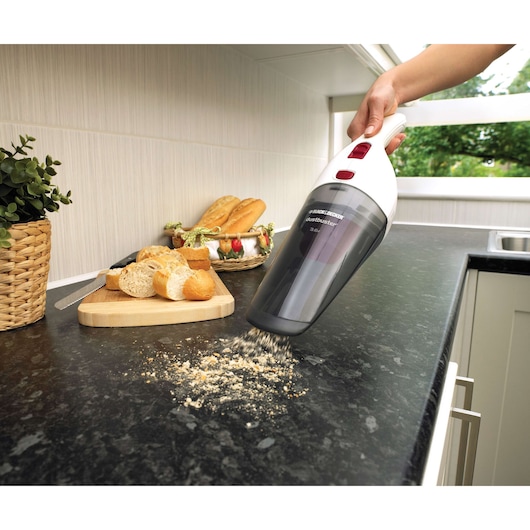 Photo of BLACKDECKER NV3620N handheld vacuum cleaning bread crumbs from a kitchen counter near a cutting board.