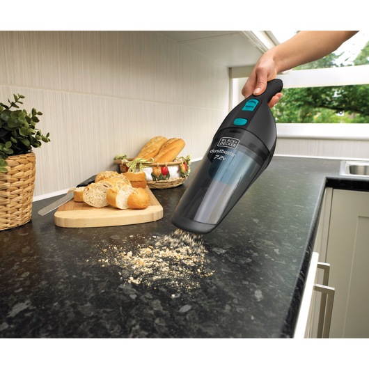 Photo of BLACK+DECKER NV7210N handheld vacuum cleaning bread crumbs from a kitchen counter.