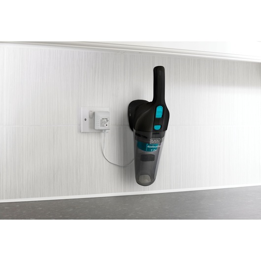 BLACK+DECKER NV7210N handheld vacuum mounted on white wall, charging with a wall adapter, side angle.