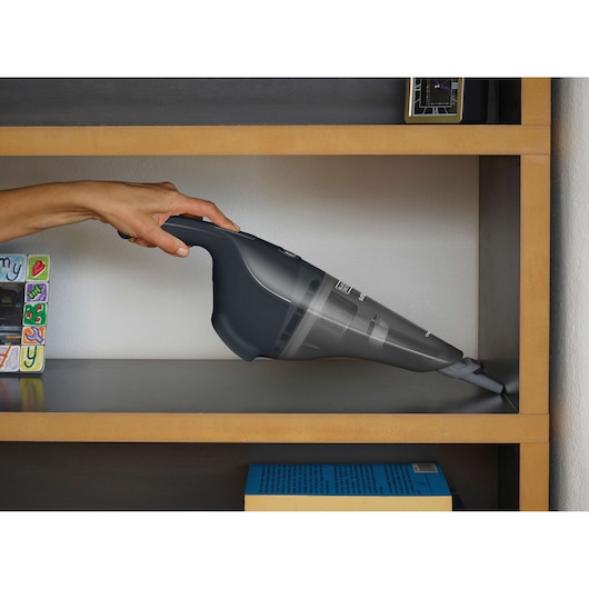 BLACKDECKER NVB215WA handheld vacuum cleaning a shelf, dark grey color, close-up photography.