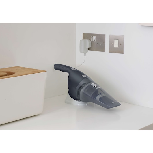 BLACK+DECKER handheld vacuum NVB215WA on charging base, angled left on white kitchen counter.