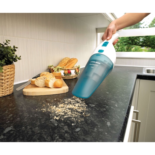 BLACKDECKER NW4820N handheld vacuum cleaning bread crumbs on kitchen countertop, bread and knife in background.