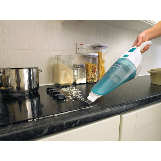 Photo of BLACKDECKER NW4820N handheld vacuum cleaning rice from a black kitchen countertop.