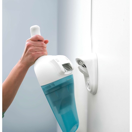 BLACKDECKER NW4820N handheld vacuum with blue dust container being placed on wall-mounted charger, close-up.