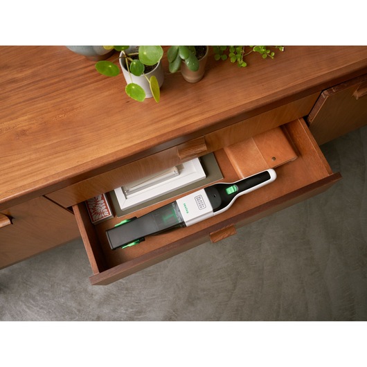 BLACKDECKER REVHV8C handheld vacuum stored in wooden drawer, white and green design, top angle.