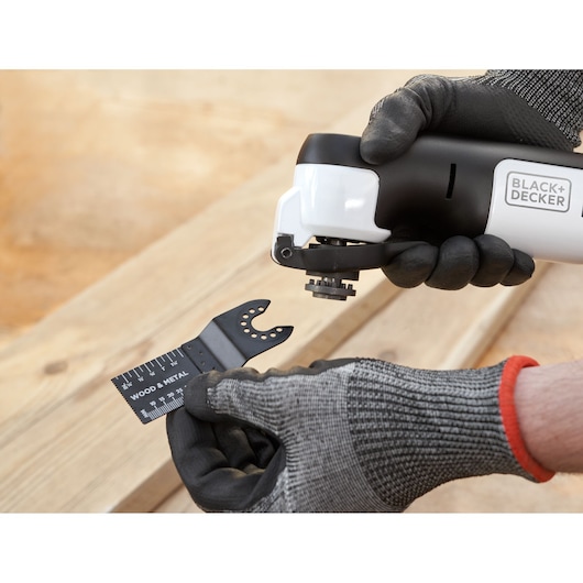 Close-up photo of BLACK+DECKER REVOS12C oscillating tool being fitted with a wood and metal cutting blade.