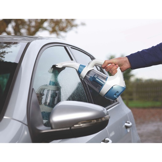 BLACK+DECKER WW100 window vacuum cleaner used on a car window, side angle, blue and white design.