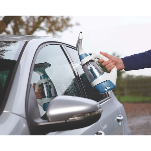 BLACK+DECKER WW100 window cleaner spraying water on a car window outdoors.