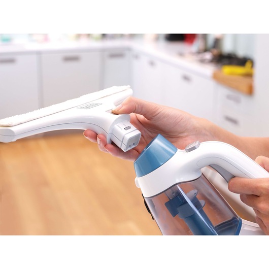 Photo of BLACKDECKER WW100 window vacuum cleaner with person attaching cleaning head in a bright kitchen.