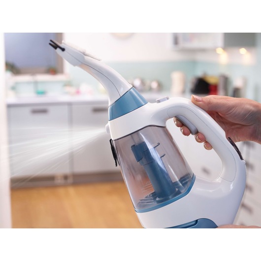 BLACK+DECKER WW100 handheld steam cleaner spraying in a kitchen, close-up of trigger handle and water tank.